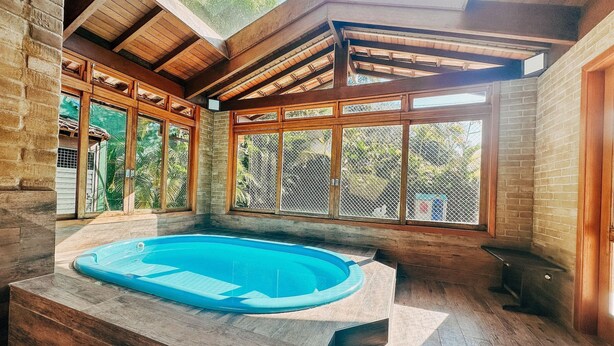 A hot tub in a wooden cabin with large windows and a view of the outdoors. - Casa Rio Habitat (Petrópolis)
