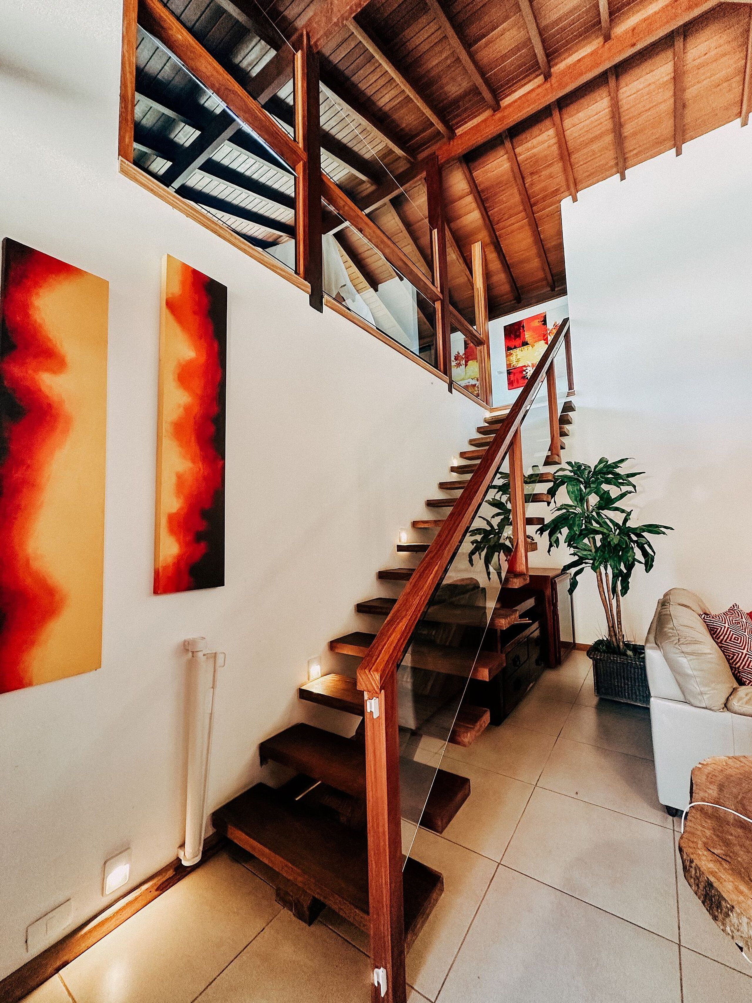 A wooden staircase with a glass railing leading to a second floor.