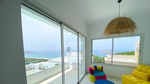 A modern living room with large windows offering a view of the sea and distant land. - Horizon Marin in Raf Raf (Raf Raf)