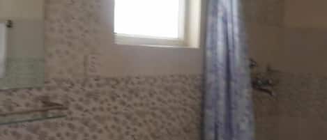 Un baño con inodoro, lavamanos y zona de ducha.