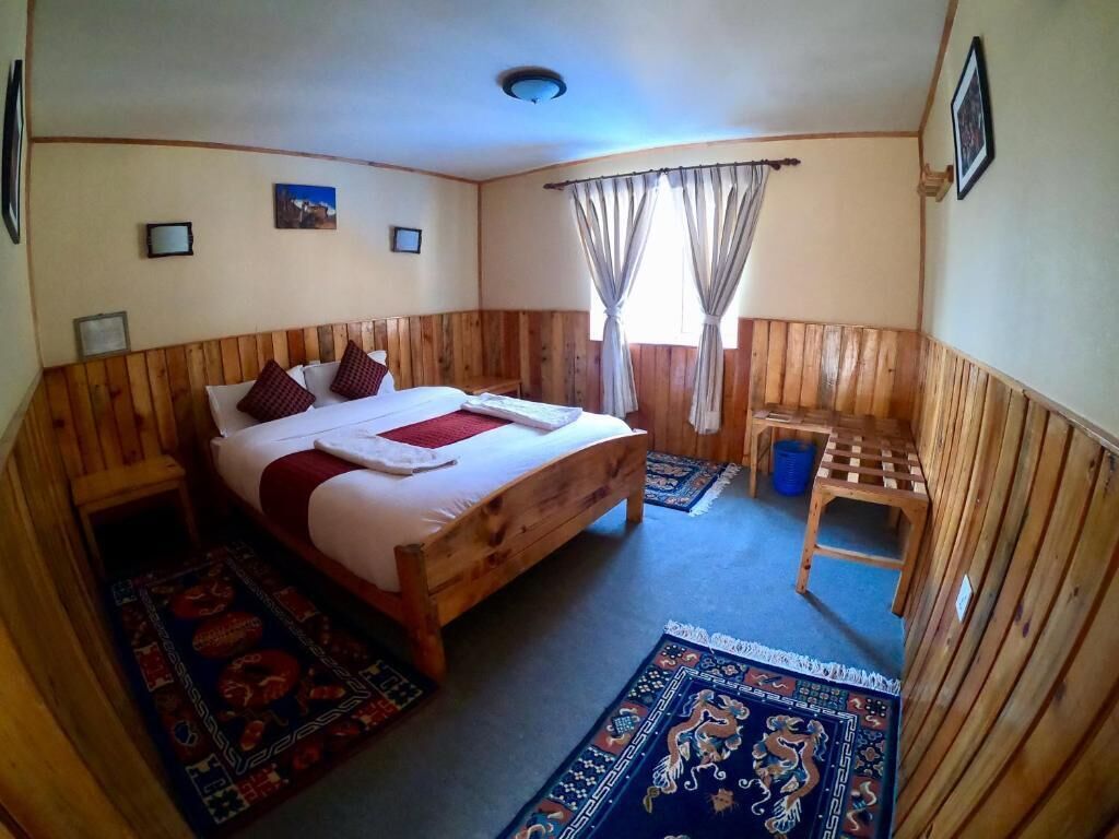 Una habitación con paneles de madera, una cama, una mesita y dos alfombras.