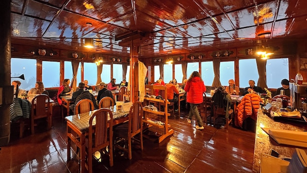 A wooden interior with tables and chairs, large windows, and a high ceiling. - Panorama Lodge and Restaurant  (Namche Bazar)