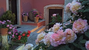 Un edificio con fachada roja, entrada de piedra y macetas con flores.