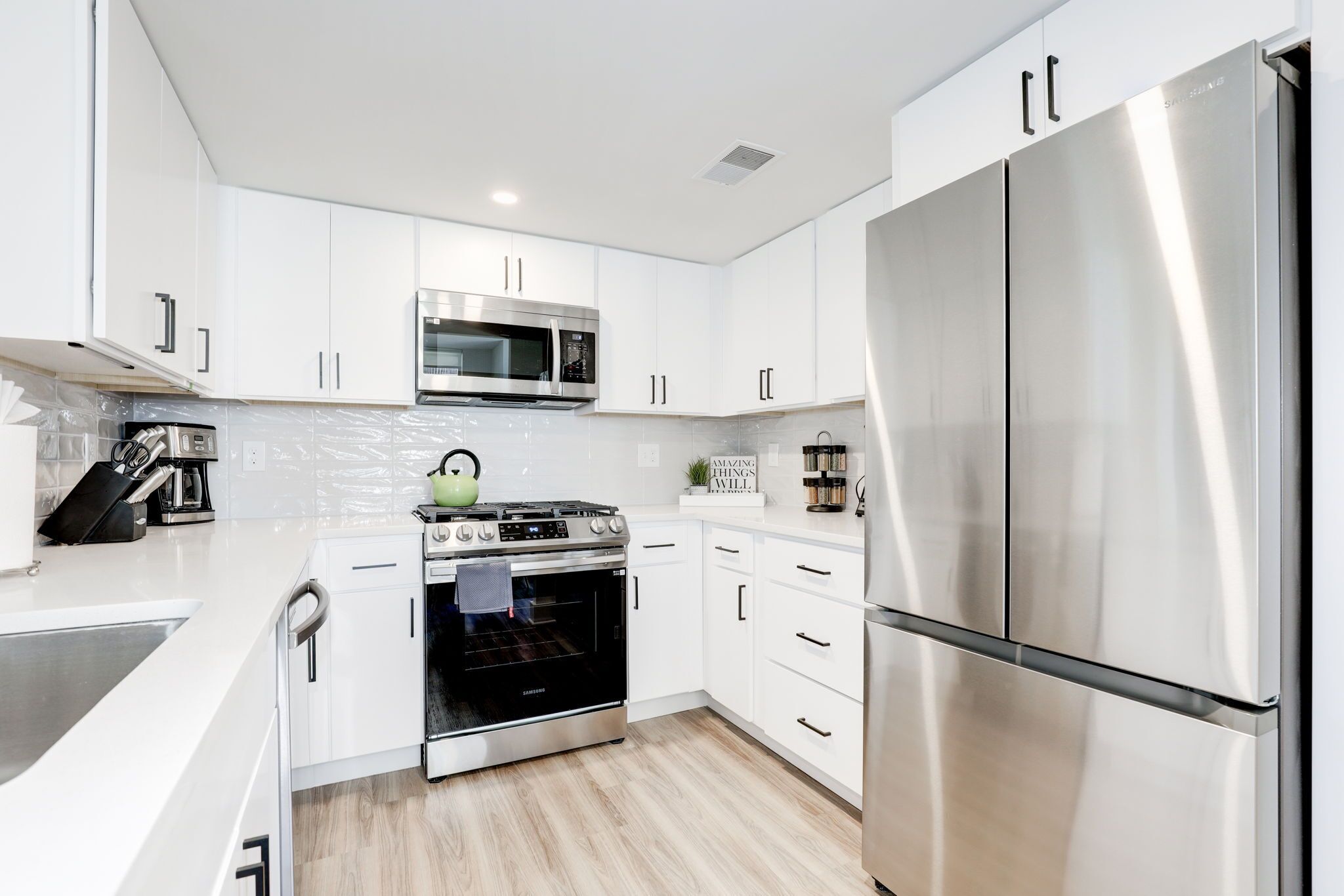 A modern kitchen with white cabinets, stainless steel appliances, and a built-in oven.