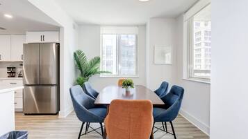 Un comedor moderno con una mesa de madera, sillas azules y una silla anaranjada en el centro.