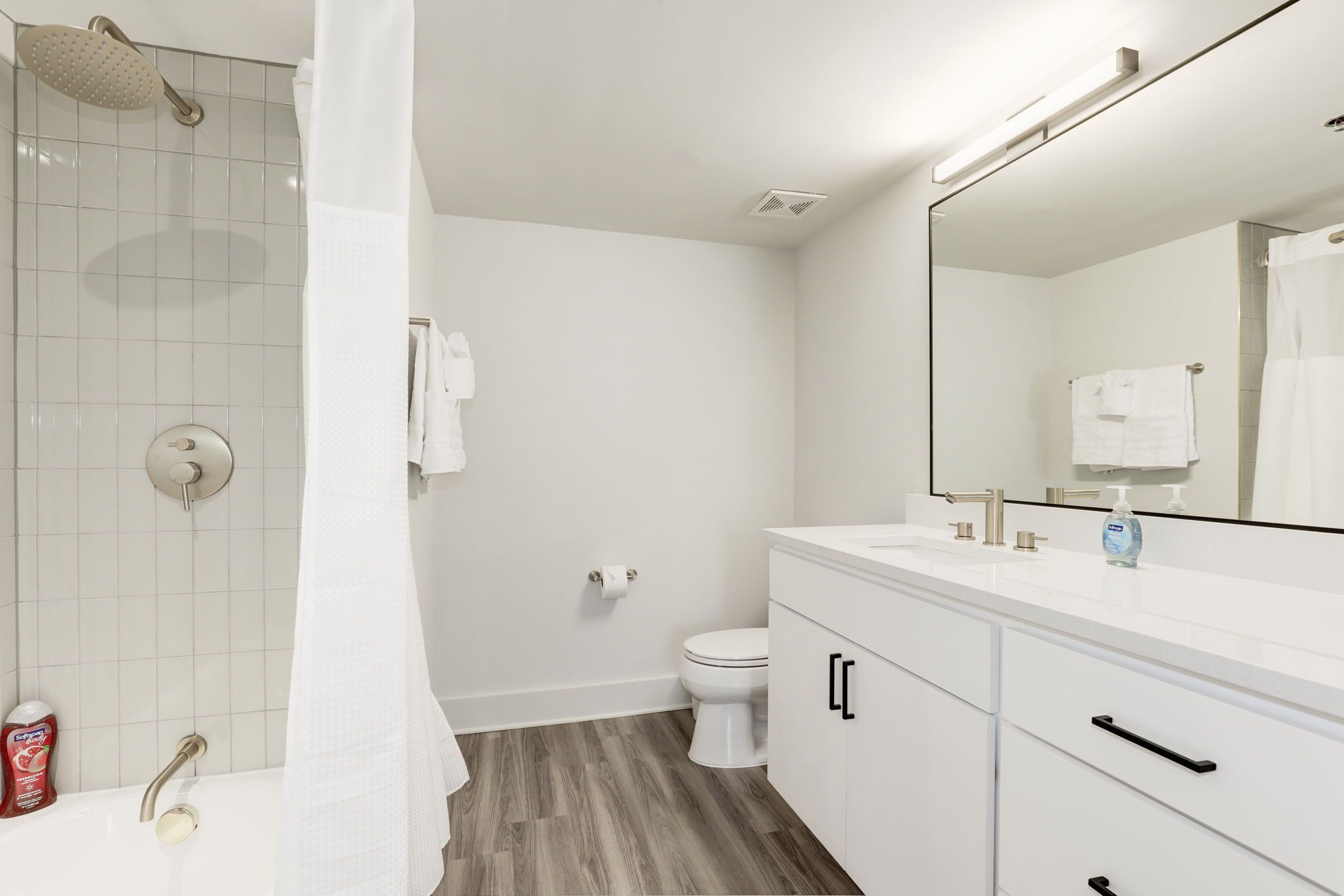 A modern bathroom with a shower, toilet, and vanity.