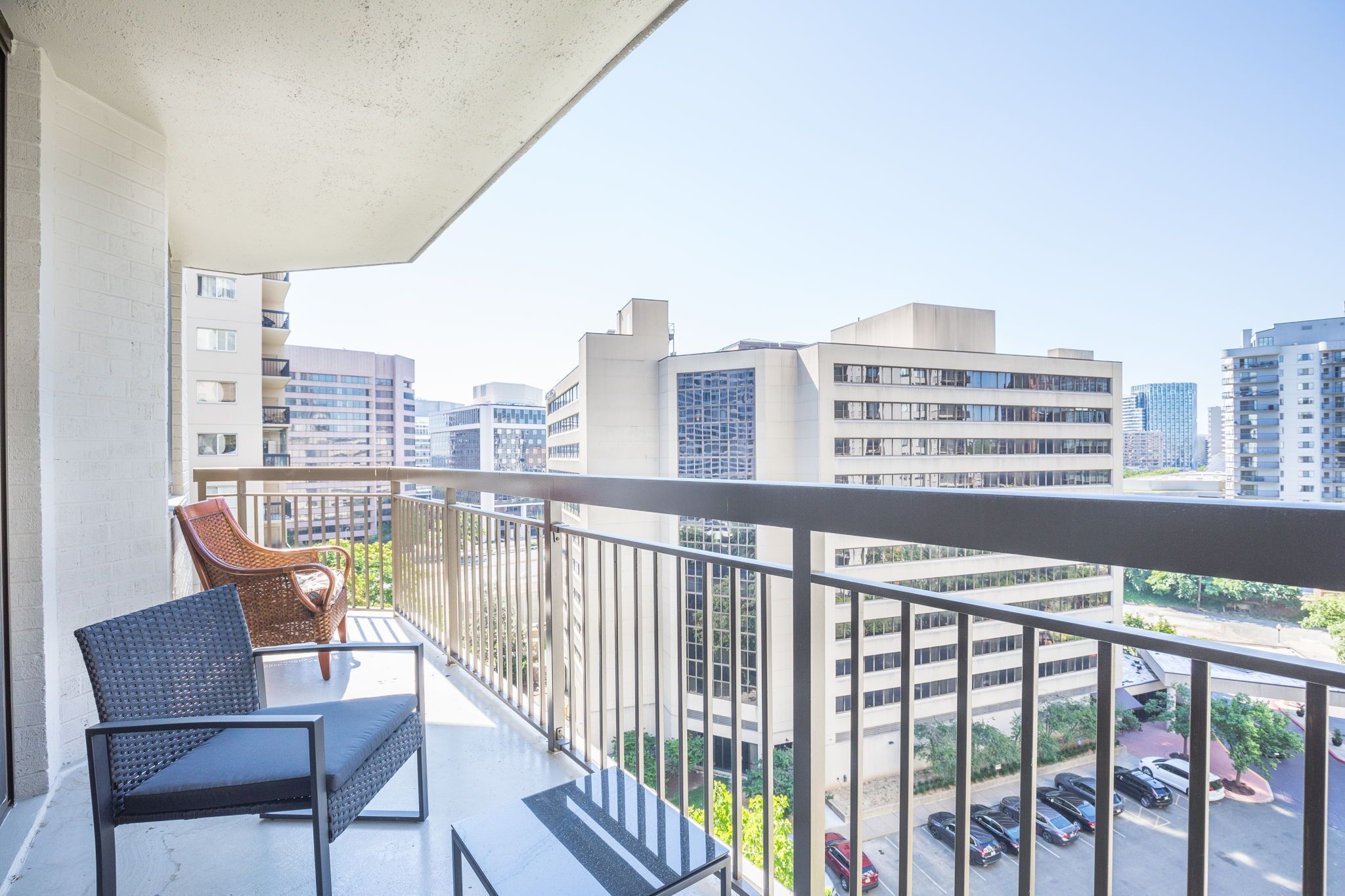 A balcony with a view of surrounding buildings and parked cars.