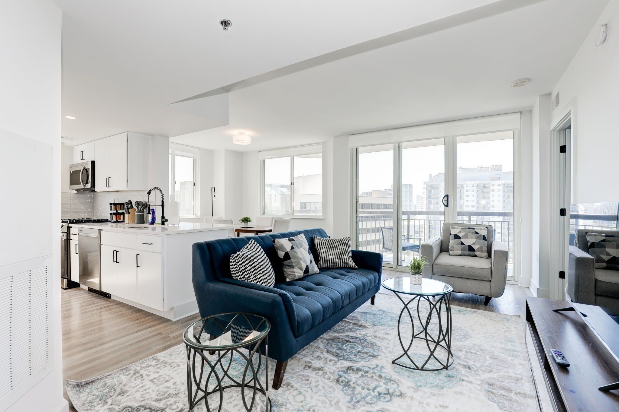 Een modern appartement met een woongedeelte, keuken en grote ramen met uitzicht over de stad.