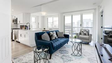 Een modern appartement met een woongedeelte, keuken en grote ramen met uitzicht over de stad.