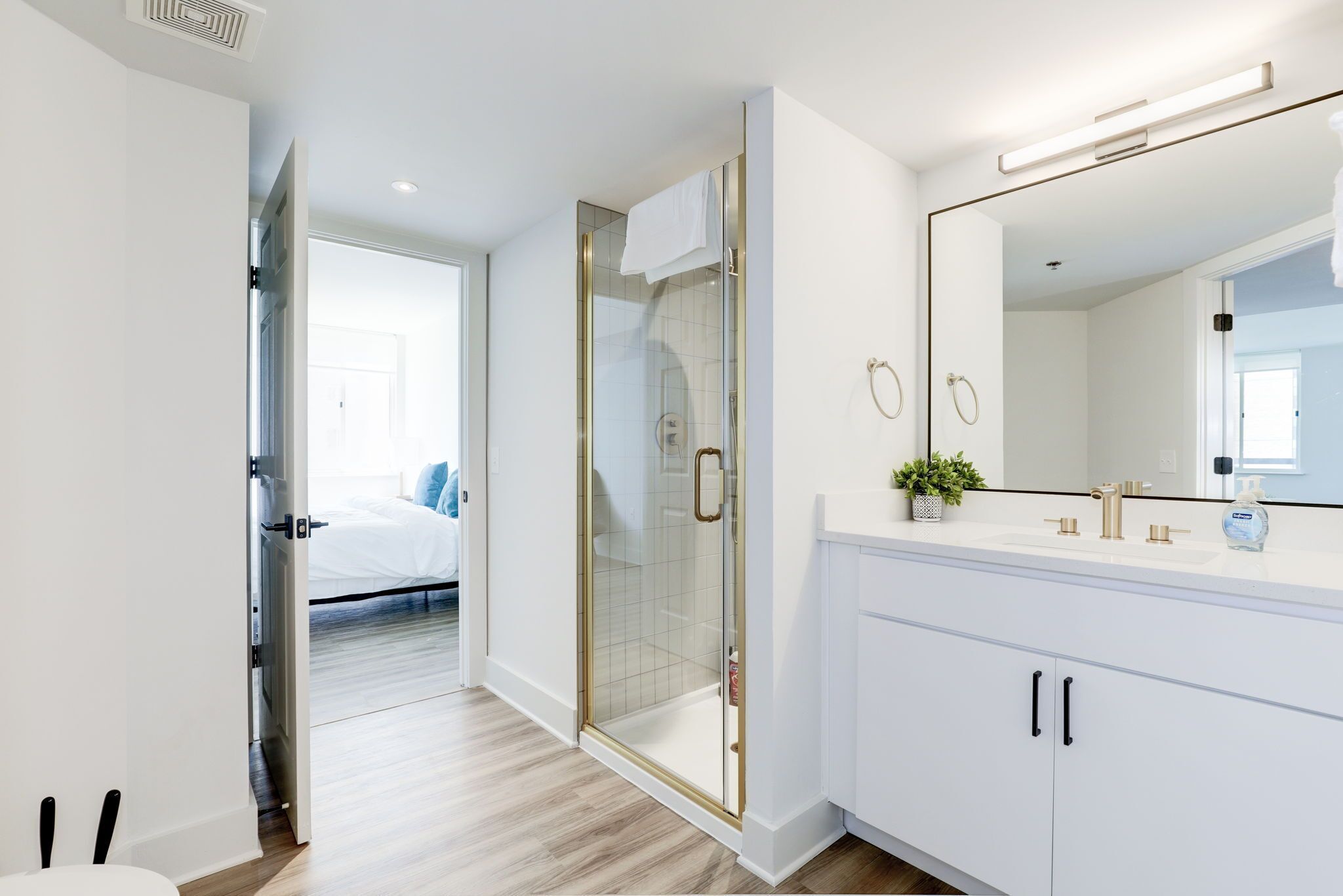 A modern bathroom with a glass shower enclosure, a large mirror, and a white vanity.