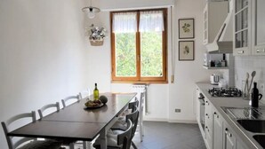 Eine Küche mit Esstisch, Stühlen, einem Fenster mit Vorhängen und einem Herd.
