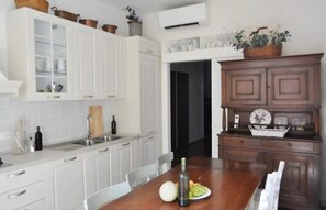 A kitchen with white cabinets, a wooden dining table, and a dark wooden cabinet with decorative items.