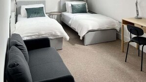 Quarto moderno com duas camas, uma escrivaninha e uma cadeira.
