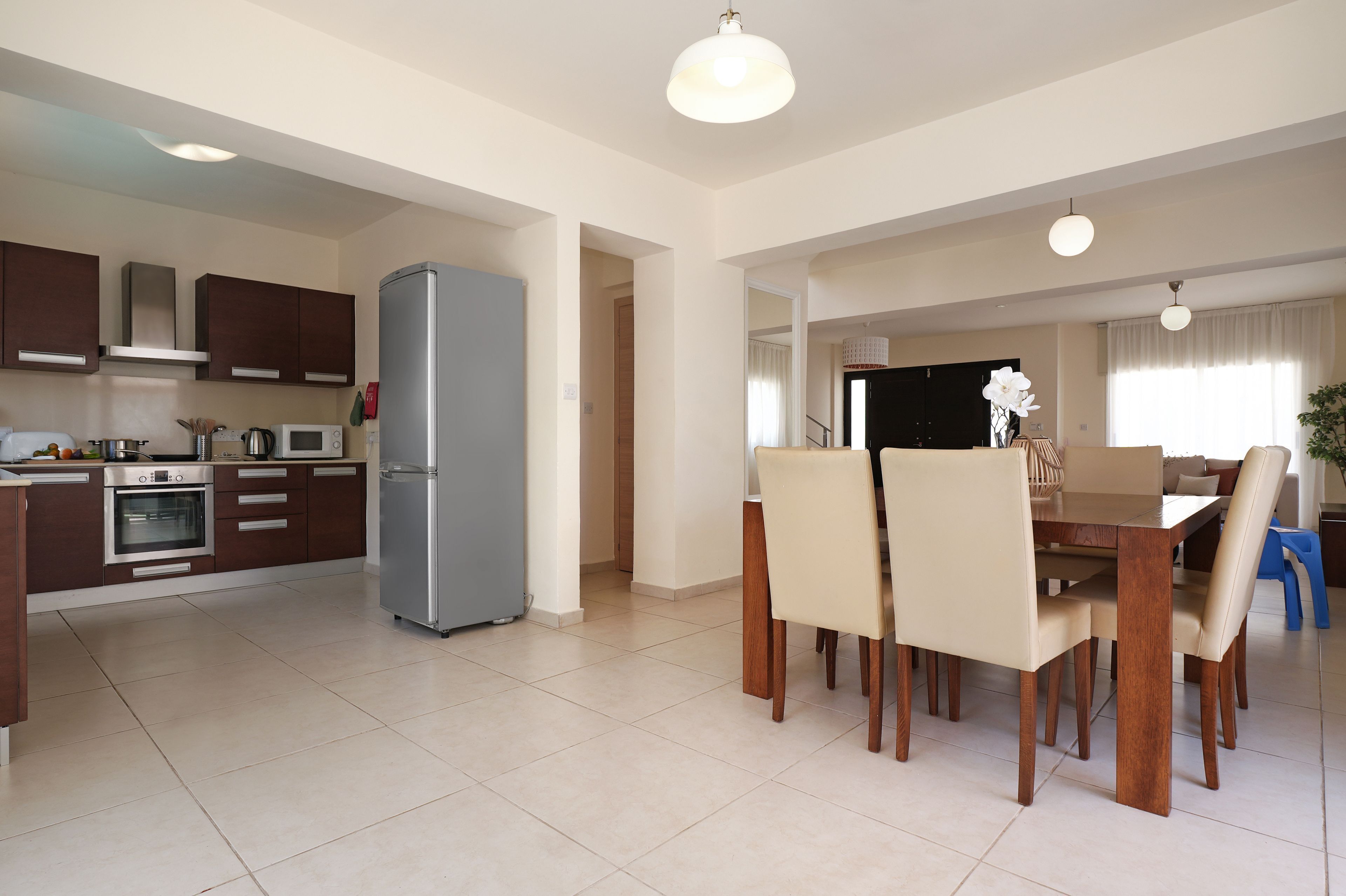 A modern kitchen with built-in appliances, a dining area with a wooden table and chairs, and a staircase leading to another level.