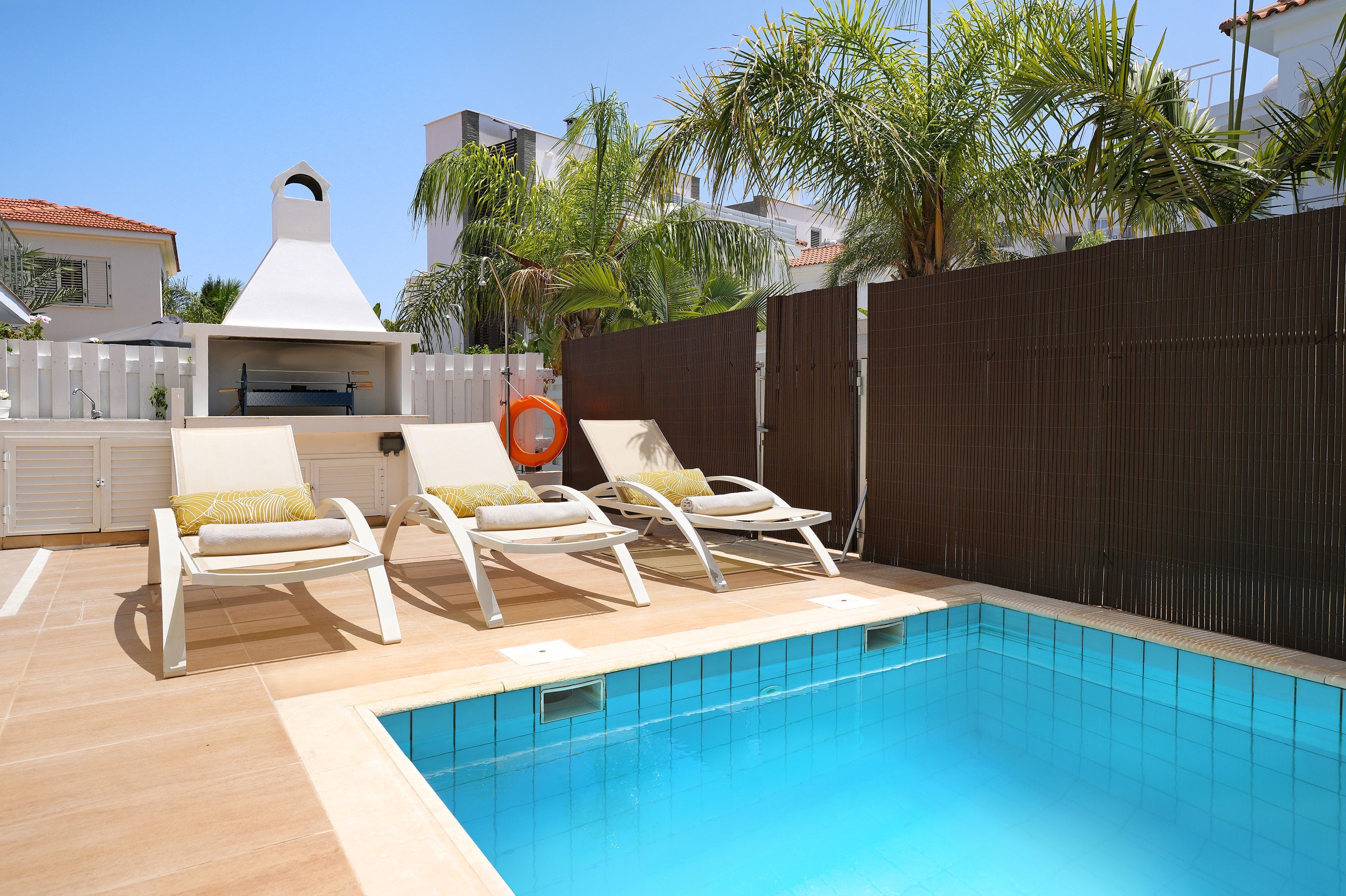 A swimming pool with lounge chairs and a barbecue area.