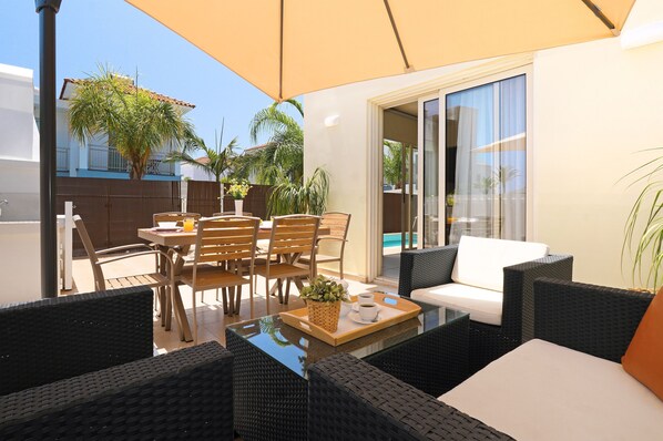 An outdoor patio with wicker furniture, a table with a tray, and a white sofa. - Villa Artemis - 30m from Pernera Beach (Pernera)