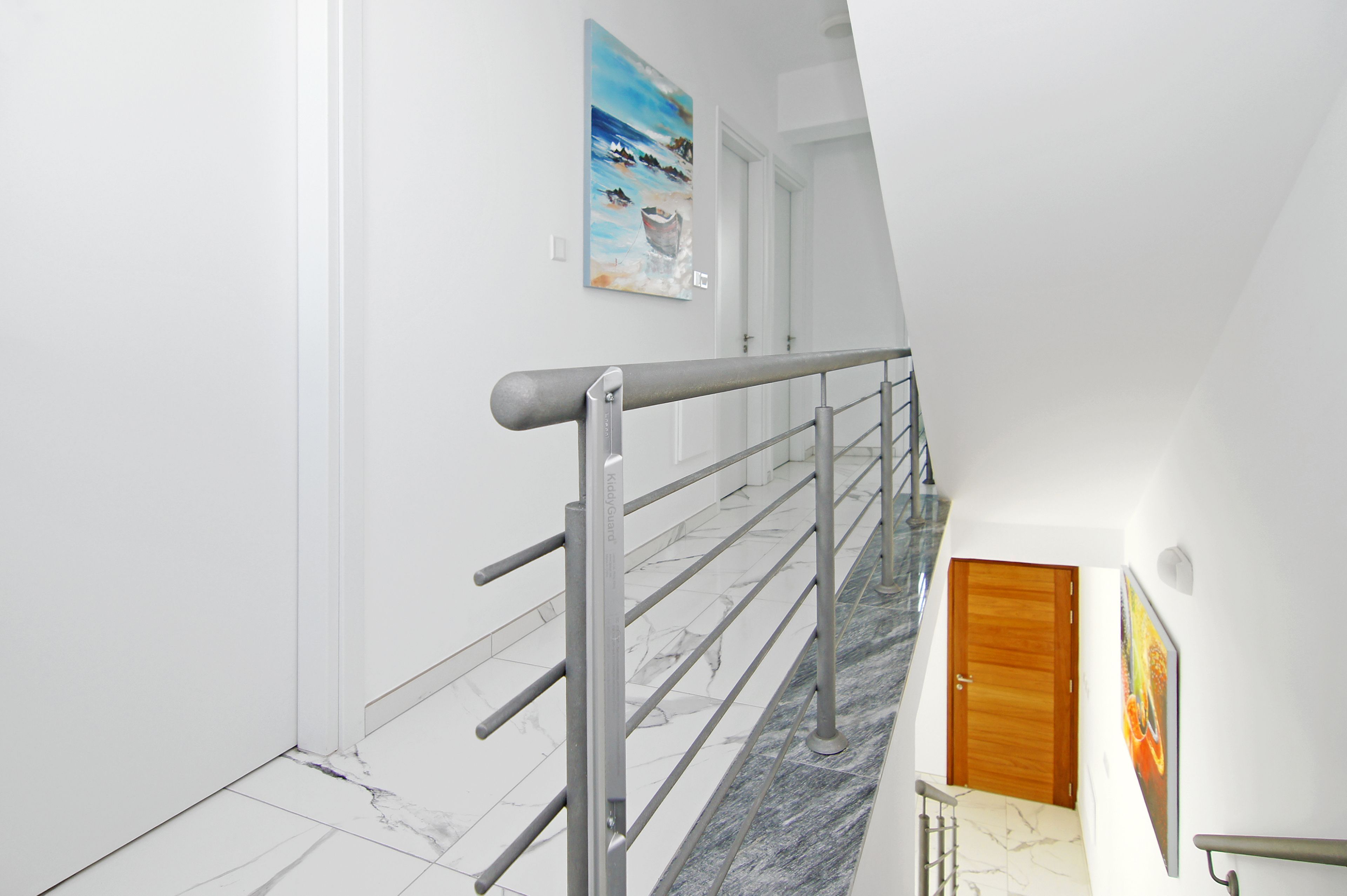 Un intérieur moderne avec un escalier en marbre, des rampes en métal et une porte en bois.