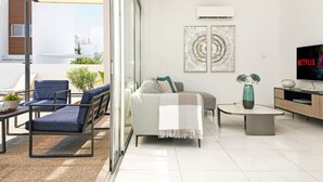 Una sala moderna con un sofá, sillones, una mesa de centro y un televisor.