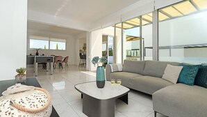Una sala de estar moderna con un sofá gris, una mesa de centro y una zona de comedor al fondo.