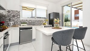 Una cocina moderna con armarios blancos, horno empotrado y una isla grande con taburetes.