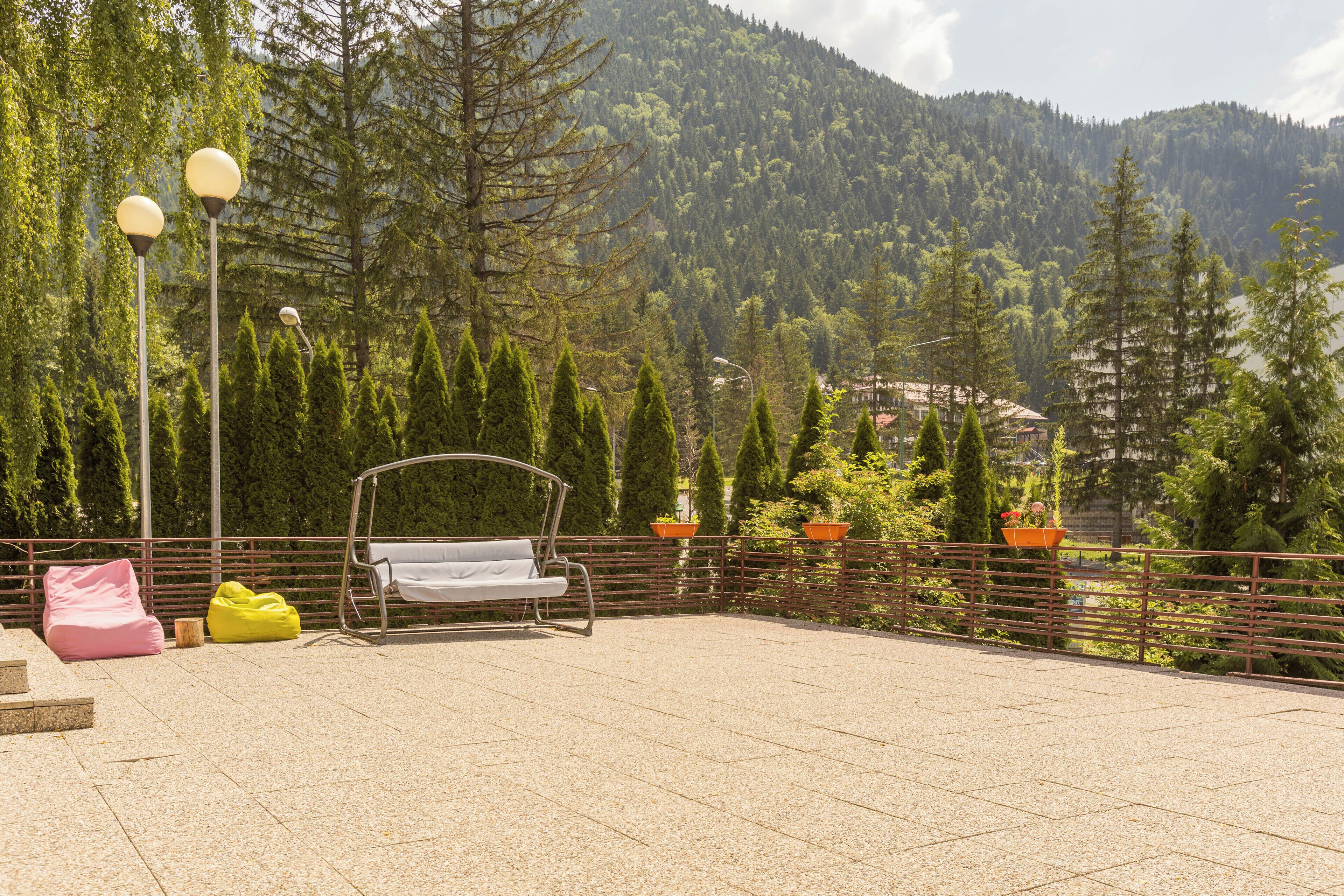 An outdoor seating area with a swing chair, benches, and potted plants.