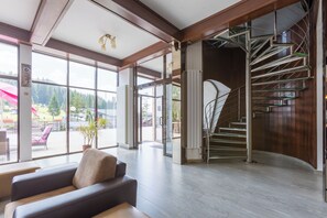 Un vestíbulo amplio con una escalera moderna, ventanas grandes que ofrecen vistas al exterior y una zona de estar con un sofá.