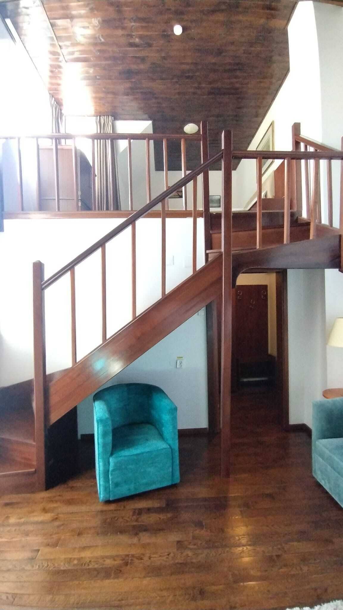 A wooden staircase leading to an upper level with a blue armchair at the bottom.