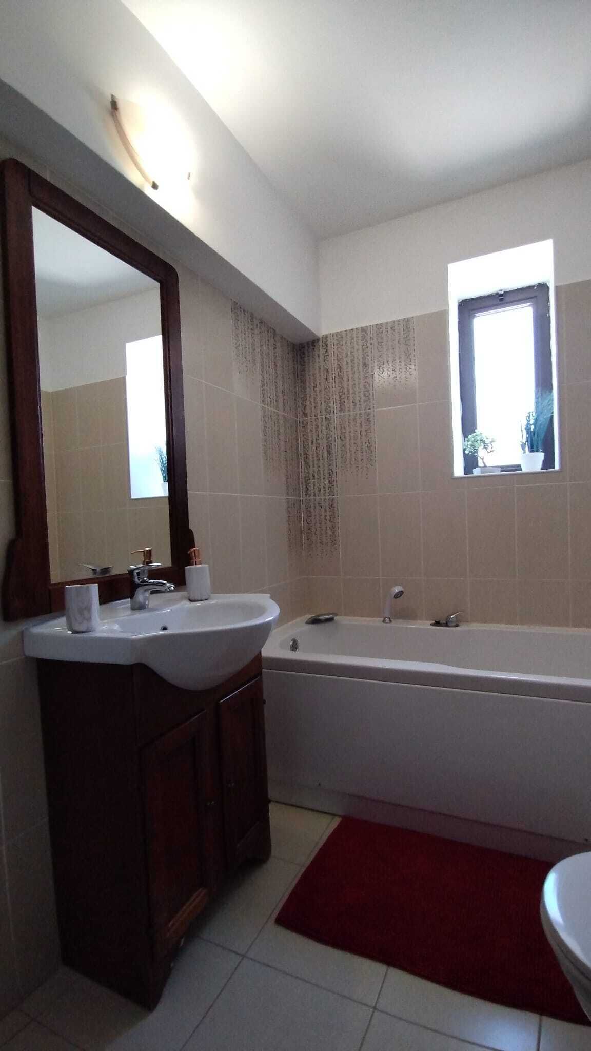 Un baño con lavabo, espejo, tocador, bañera y ventana.