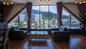 Ein Zimmer mit einem großen Fenster, zwei Sofas, einem Tisch und einer Lampe.