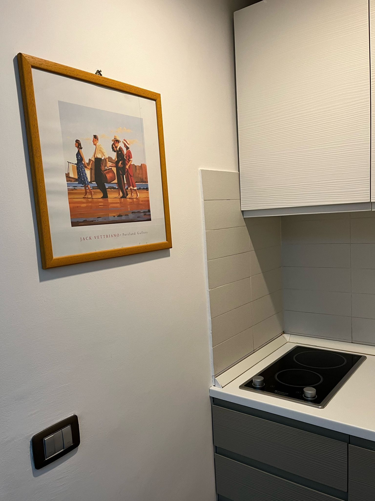 A kitchen with a framed artwork, a stove, and cabinets.