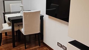 A compact kitchen with a dining area, a built-in TV, and a white refrigerator. - 108 APARTMENT (Turin)