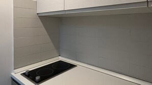 A kitchen with white cabinets, a black stovetop, and a tiled backsplash. - 108 APARTMENT (Turin)