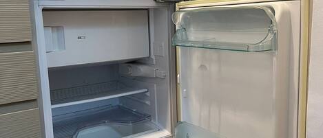 Een compacte koelkast met een vriesvak aan de rechterkant en een hoofdcompartiment aan de linkerkant, beide met glazen deuren.