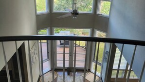 A view from a balcony with a ceiling fan, large windows, and a view of a deck area. - Beautiful 5BR home on 1 acre in Highlands Ranch perfect for families (Littleton)