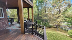 A wooden deck with a black railing, a brick wall, and a patio area with outdoor furniture. - Beautiful 5BR home on 1 acre in Highlands Ranch perfect for families (Littleton)