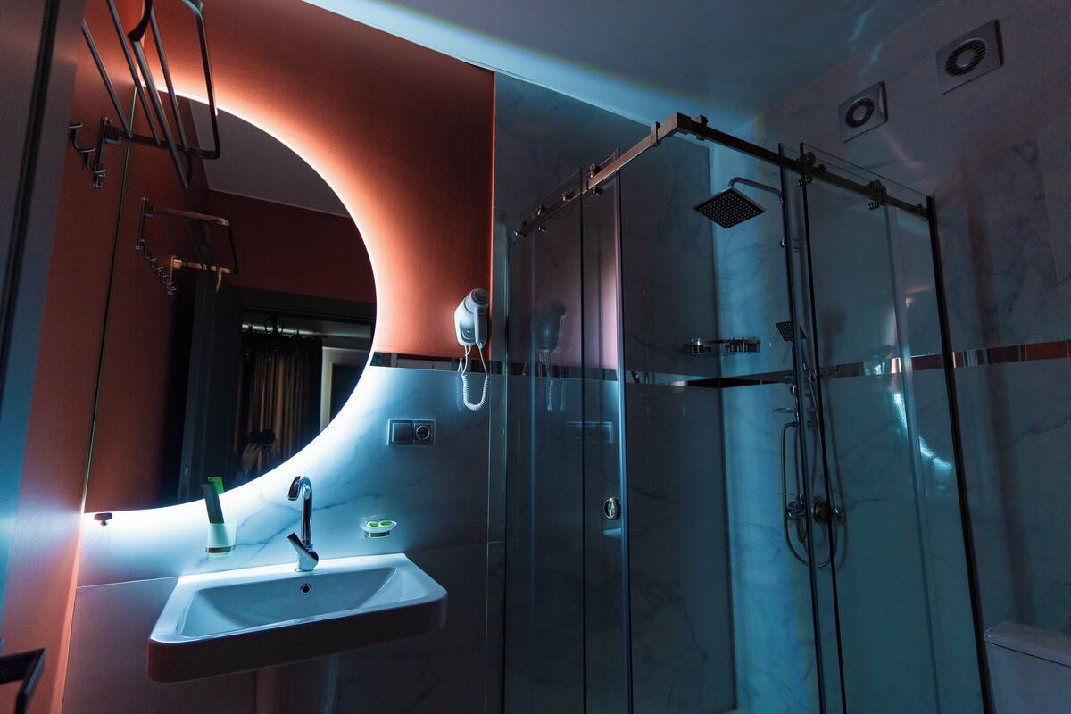A modern bathroom with a glass-enclosed shower, a built-in sink, and a large mirror.