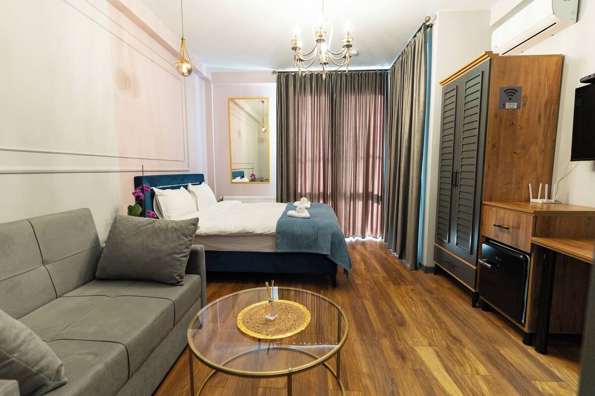 A hotel room with a bed, a sofa, a small table, a TV, and a wardrobe.