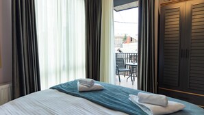 Una habitación de hotel con cama, balcón y vistas al exterior.