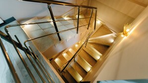 Una escalera moderna con barandillas de metal y peldaños iluminados.