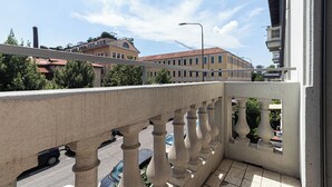 A balcony with a stone balustrade overlooking a street with parked cars and buildings in the background. - Italianway Easy - Ponti 7 (Milan)
