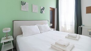 A neatly made bed with white linens and pillows, a bedside table with a lamp, and wall art above the bed. - Italianway Easy - Ponti 7 (Milan)