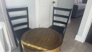A round wooden table with two dark wooden chairs, a white door, and a bed with white bedding in the background. - Pent House with Roof Deck near Capitol Hill - U5 (Washington)