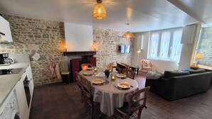 Un'accogliente sala da pranzo con parete in pietra, camino e TV a parete.