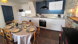 Una cucina compatta con mobili bianchi, forno a incasso e piano cottura.