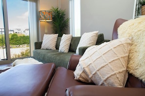 A living room with a sofa, a chair, and a view of the outdoors. - Gwyn For Beach Apartment, Aberporth (Aberporth)