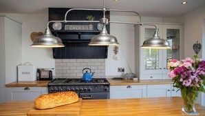 Une cuisine équipée d’une cuisinière, de deux lampes suspendues, d’un grille-pain et d’une miche de pain posée sur le comptoir.
