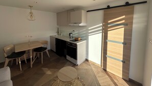 A modern kitchen with a dining area, a coffee machine, and a sliding door. - Escapade à 2 Bien Être et Déconnexion ! Jacuzzi Privatif (Roumens)