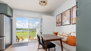 Eine moderne Küche mit integriertem Kühlschrank, einem Esstisch mit Stühlen und Seeblick durch große Schiebeglastüren.