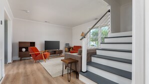 Ein modernes Wohnzimmer mit Treppe, Holzboden und einem Flachbildfernseher.