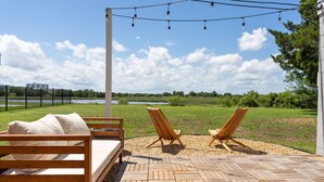 Eine Terrasse mit einer Holzbank, zwei Holzstühlen und Lichterketten.